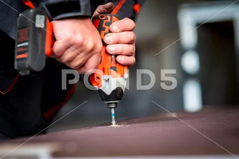 Worker tightens a screw with an electric screwdriver Stock Photos