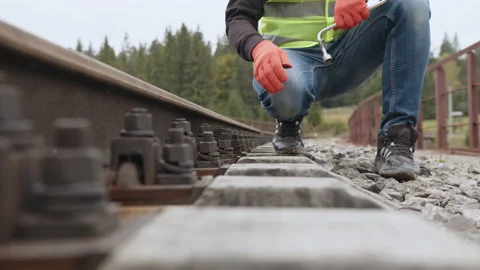 Worker tightens the screw on railroad. Engineer walking and check track work on Stock Footage 186921841