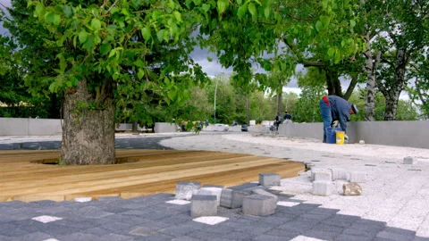 Worker tiling sidewalks with stone slabs in park at daytime Stock Footage 246472363