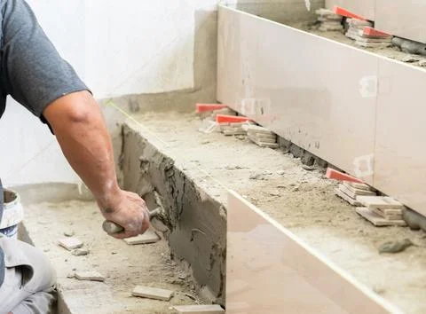 Worker  tiling stairs, applying adhesive on step. Stock Photos