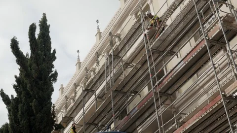Worker on top of a scaffold is sending down piece of metal using a pulley. Stock Footage 122012194