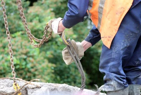Worker touches the crane hooks to the loops in the concrete slab Stock Photos