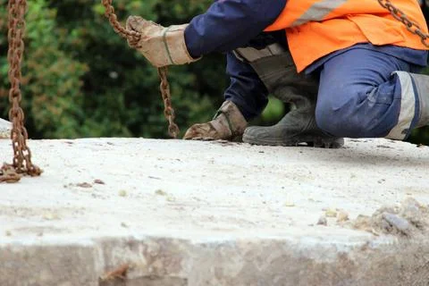 Worker touches the crane hooks to the loops in the concrete slab during re... Stock Photos