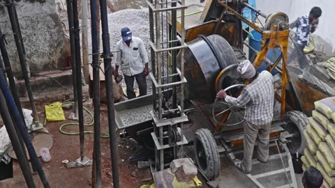 Worker transferring concrete mixer from rotating drum to lift trolley at Stock Footage 320398161