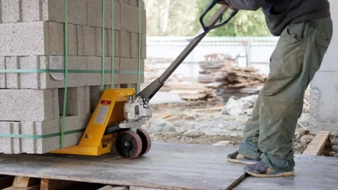 Worker Transporting Concrete Blocks on Dolly Stock Footage 277875920