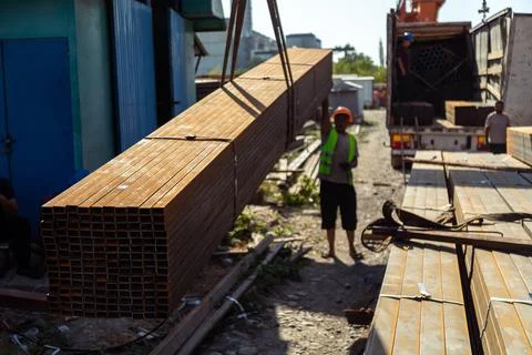 Worker transporting stack of metal pipes with gantry crane Stock Photos