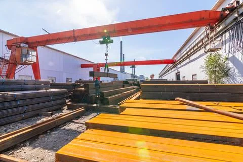 Worker transporting stack of metal pipes with gantry crane Stock Photos