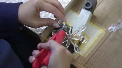 Worker trimming clear optical lens elements from injection mold sprue using red Stock Footage 334965639