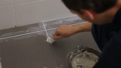 Worker troweling joints between tiles on floor Video stock 128416794