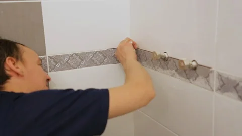 Worker troweling joints between tiles on wall Stock Footage 128417034