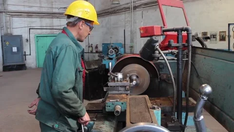 Worker - a turner processes a metal workpiece on a lathe and controls Stock Footage 124576628