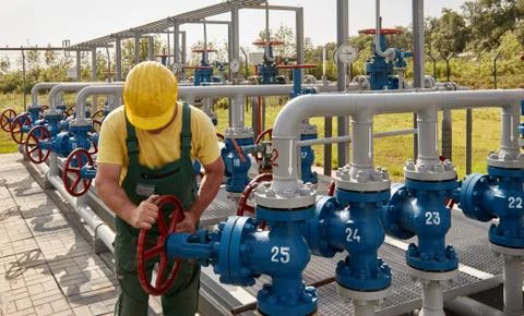 Worker turns a valve in a gas processing plant Stock Photos