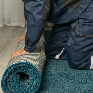 Worker twists the carpet, help with moving. Relocation services Foto stock