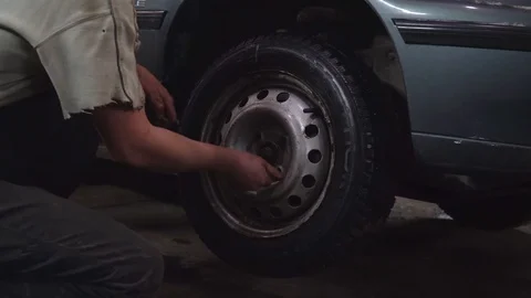 The worker twists the nuts on the wheel Video stock 84284382