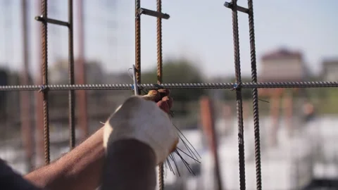 The worker twists the reinforcement with wire at the construction site Stock Footage 159953278
