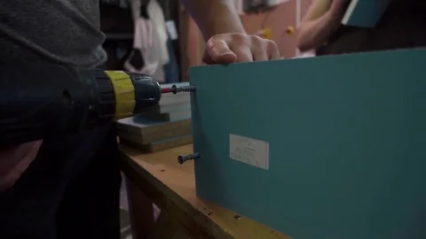 A worker twists the screw into the board with a device screwdriver Stock Footage 76915028