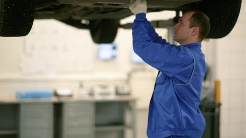 The worker twists the screws in the protective sheet on the bottom of the car Stock Footage 80469926