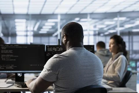 Worker typing code on PC to mend data center racks Stock Photos