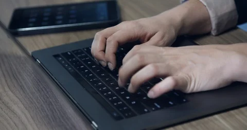 Worker typing on modern laptop computer with smartphone in background Stock Footage 118849259
