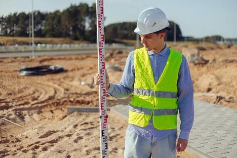 Worker is unfolding leveling rod on construction site. Stock Photos