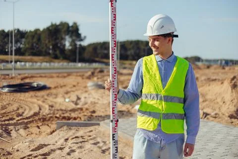 Worker is unfolding leveling rod on construction site. Stock Photos