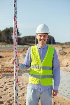 Worker is unfolding leveling rod on construction site. Stock Photos