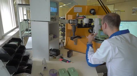 Worker in uniform checking quality of processed tool using optical device Stock Footage 65001239