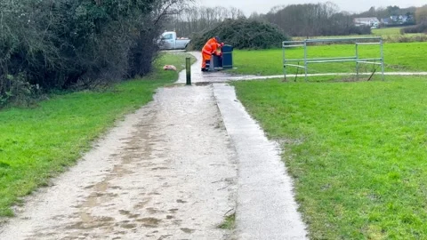 Worker in uniform cleaning up trash with a garbage bag in an urban area Stock Footage 302471239