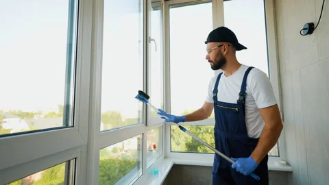 Worker in Uniform Cleaning Window for a Streak-Free Finish Stock Footage 289778565