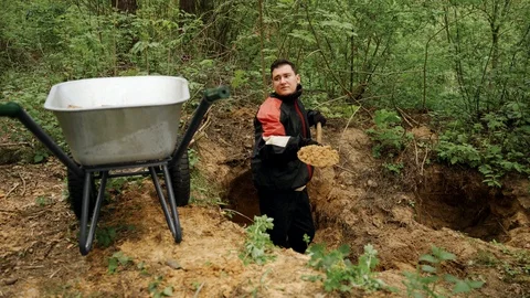 Worker in uniform digs a hole with a shovel in the forest and extracts sand Vídeos de archivo 130168650