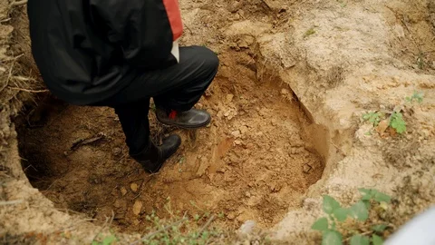 Worker in uniform digs a hole with a shovel in the forest and extracts sand Stock Footage 130168702