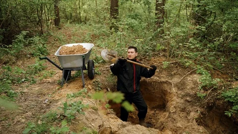 Worker in uniform digs a hole with a shovel in the forest and extracts sand Vídeos de archivo 130168891
