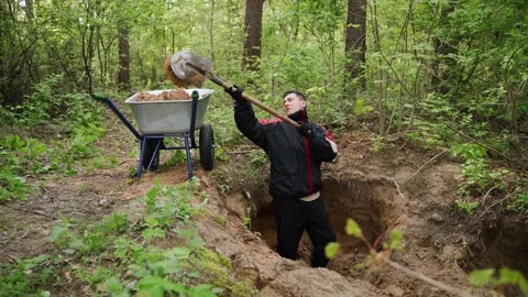 Worker in uniform digs a hole with a shovel in the forest and extracts sand Stock Footage 150659677