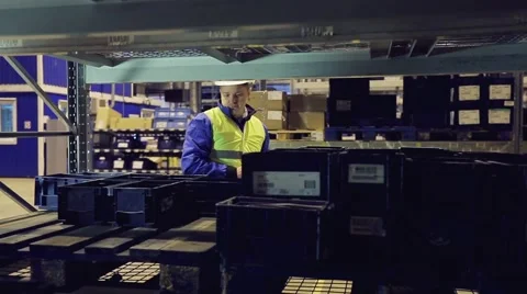 Worker in uniform going along shelves and checking cagro Stock Footage 61122910
