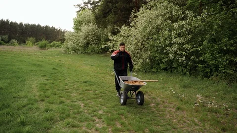 Worker in uniform going with wheelbarrow in the forest with sand. Hard work Stock Footage 130169009