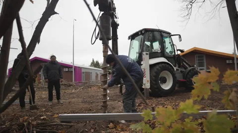 Worker in uniform holds large bore of tractor to drill pit Stock Footage 312408545