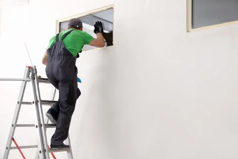 Worker in uniform installing double glazing window indoors Stock Photos