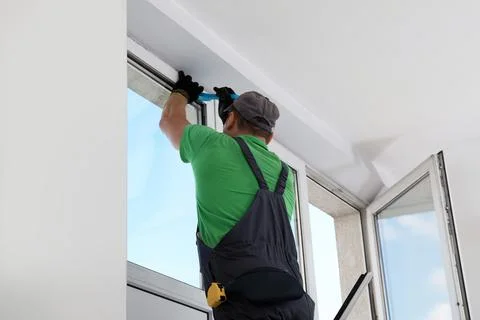 Worker in uniform installing window indoors, back view Stock Photos
