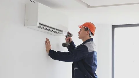 Worker in uniform sets air conditioning Stock Footage 70419306