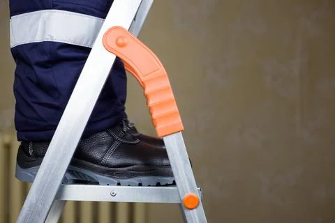 Worker in uniform on stepladder Stock Photos