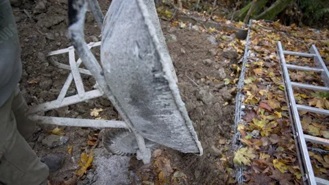 Worker unloads a wheelbarrow full of soil Stock Footage 158975042