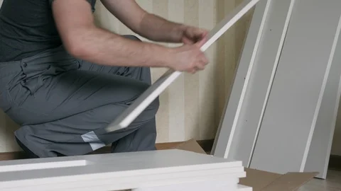 Worker Unpacks Elements Of White Wooden Furniture Before Assembling Stock Footage 116245449