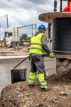 Worker unrolls black wire electrical cable Stock Photos