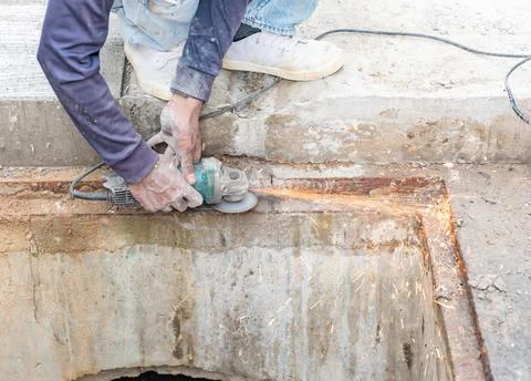 Worker use angle grinder cutting edge of water drain. Stock Photos