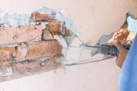 Worker use demolition hammer drill to break up wall surface. Motion blur Stock Photos