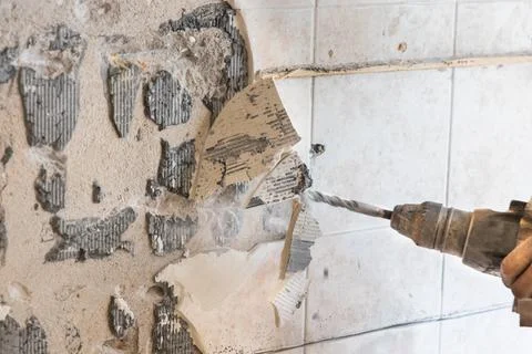 Worker use demolition hammer drill to break up tiles from wall surface. Motion Stock Photos