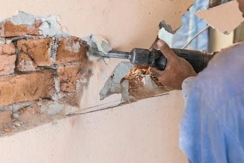 Worker use demolition hammer drill to break up wall surface. Motion blur Stock Photos