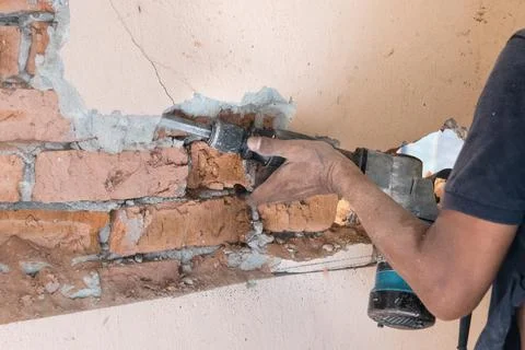 Worker use demolition hammer drill to break up wall surface. Motion blur Stock Photos