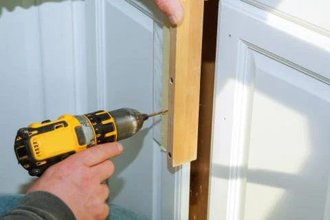 Worker use drill to repair furnitureand drills the cabinet door Stock Photos