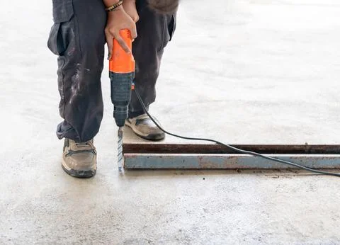 Worker use electric drill drilling cement floor for install bolt. Stock Photos
